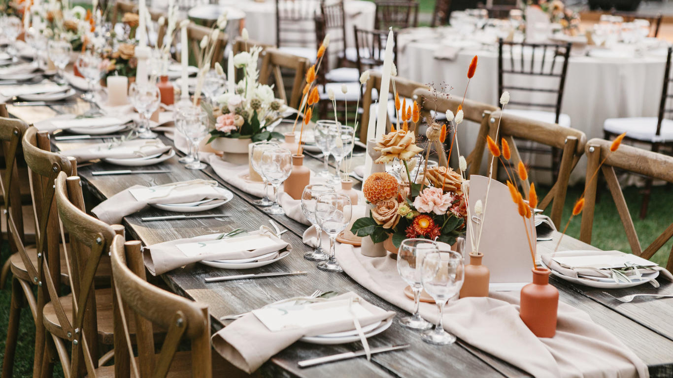 A long harvest table set with amber and orange florals
