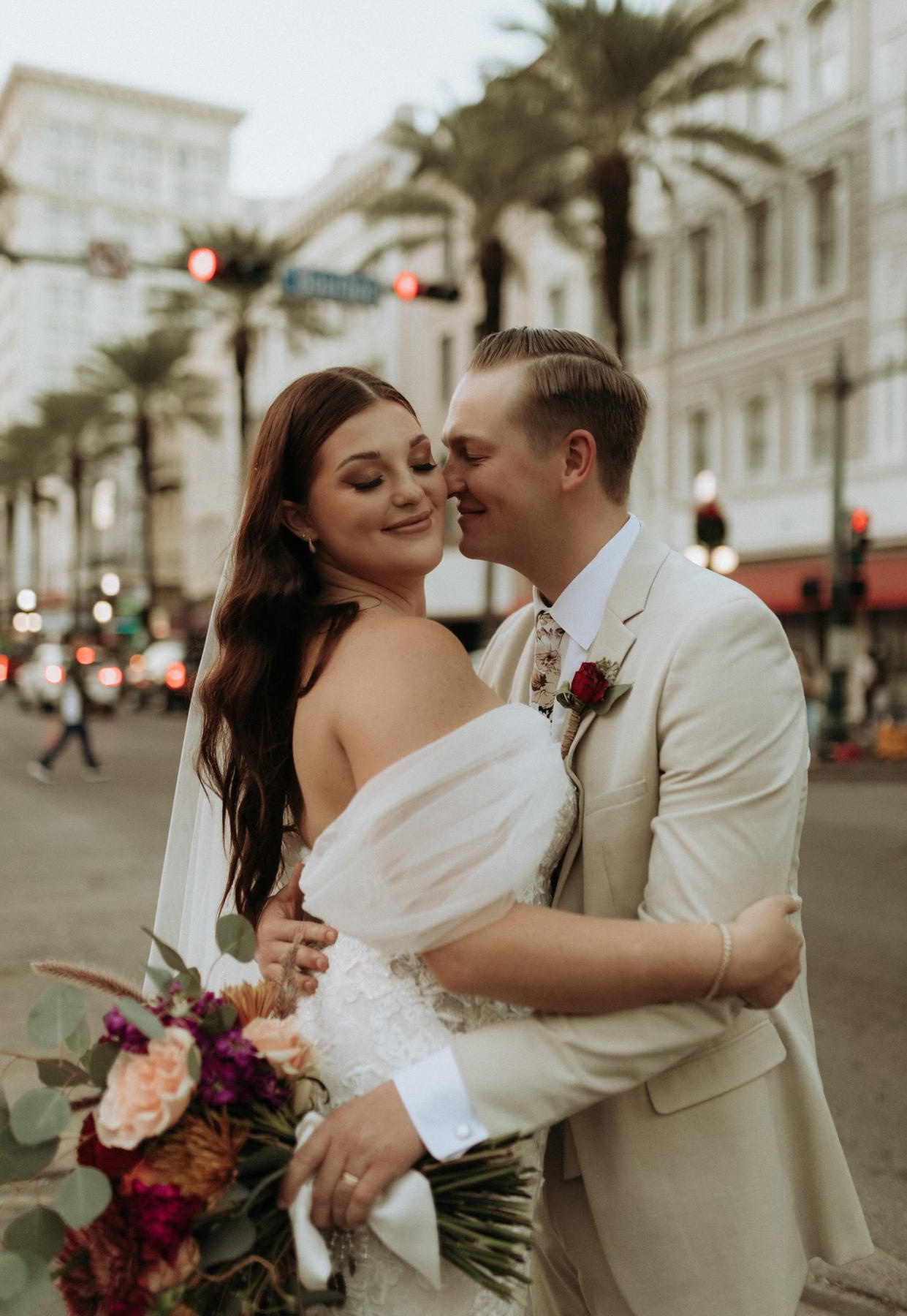 A couple embracing on a New Orleans street, bouquet in hand